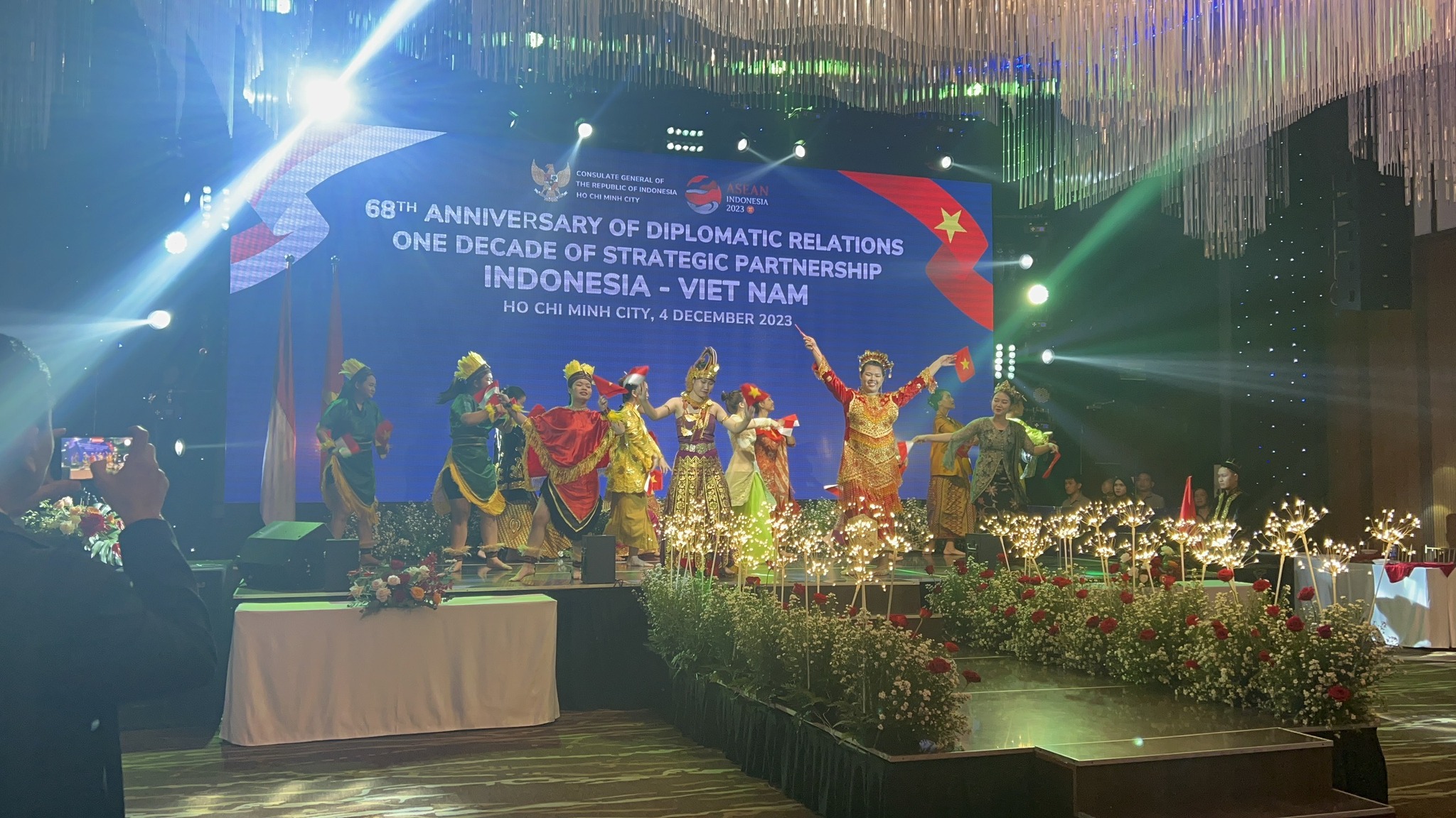 May be an image of 3 people, lighting, dais and text that says '..... 68TH ANNIVERSARY ONE DECADE DIPLOMATIC RELATIONS STRATEGIC PARTNERSHIP M CITY, 4DECEMBER 2023 INDONESIA Ho CHI MINH'